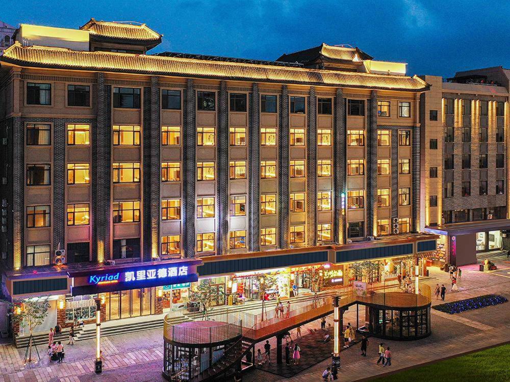 um grande edifício com pessoas andando na frente dele em Kyriad Marvelous Hotel Weihai Happy Gate Weigao Plaza em Weihai