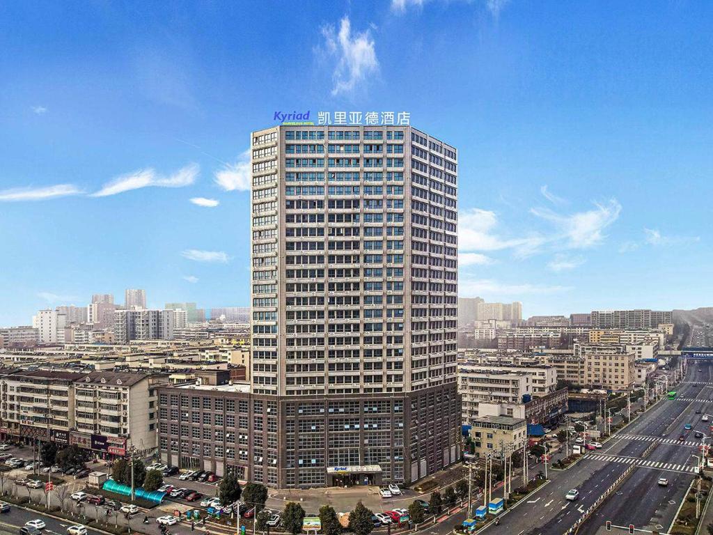 een hoog gebouw midden in een stad bij Kyriad Marvelous Hotel Henan Xinyang Pingqiao Plaza in Xinyang