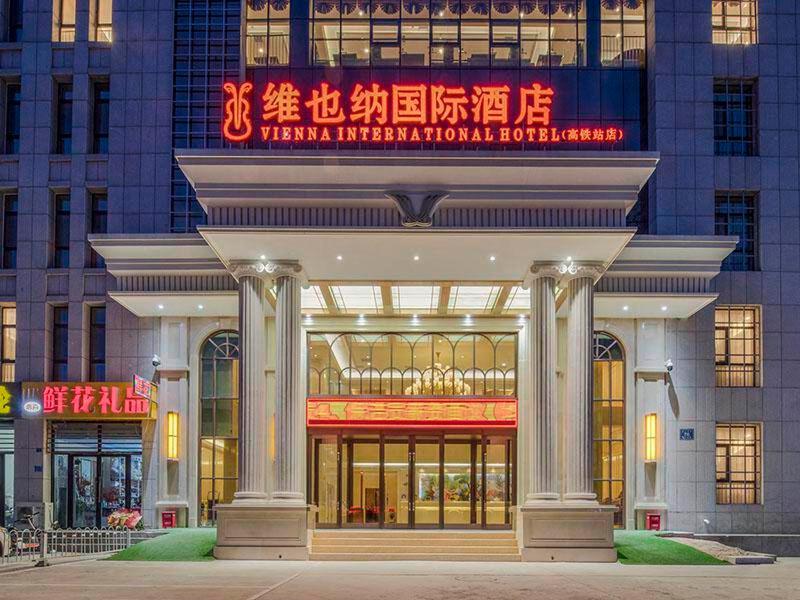 a large building with a sign in front of it at Vienna International Hotel Mongolia Chifeng High-Speed Railway Station in Chifeng