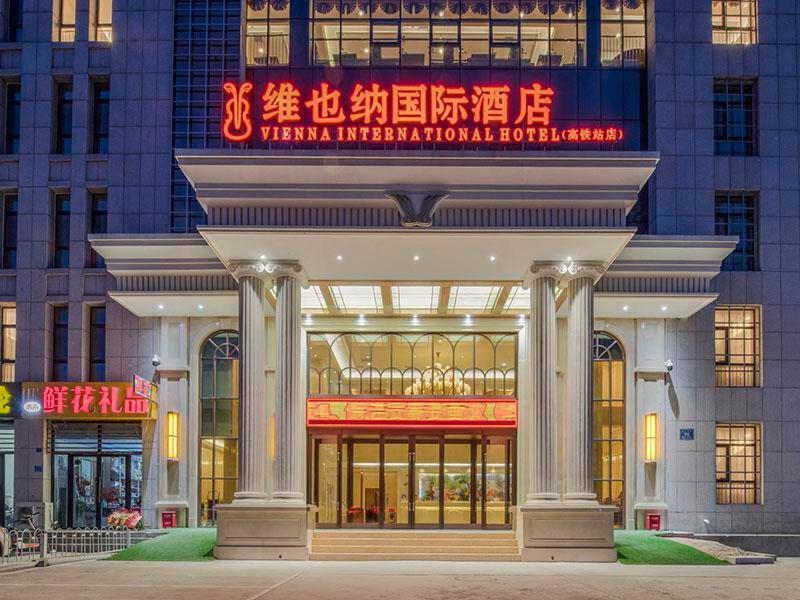 un grand bâtiment avec un panneau devant lui dans l'établissement Vienna International Hotel Mongolia Chifeng High-Speed Railway Station, à Chifeng
