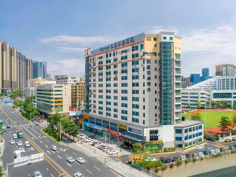 a large white building with cars on a city street at Kyriad Marvelous Hotel Shenzhen North Railway Station Yousong in Tiantangwei