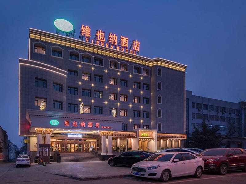 duży budynek z samochodami zaparkowanymi przed nim w obiekcie Vienna Hotel Huaidong Road Yuncheng w Yuncheng