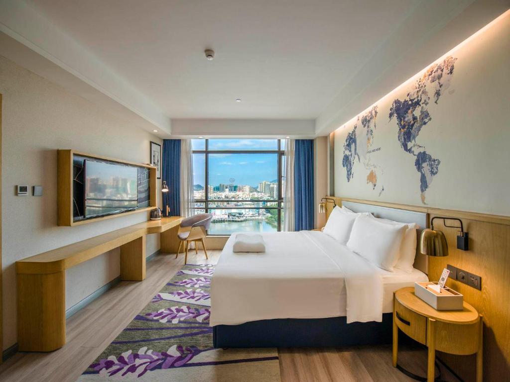 um quarto de hotel com uma cama grande e uma janela grande em Kyriad Marvelous Hotel Qingyuan City Square em Qingyuan