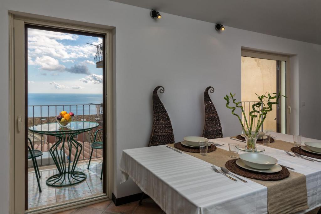 - une salle à manger avec une table et une vue sur l'océan dans l'établissement Giasone Apartments, à Taormine