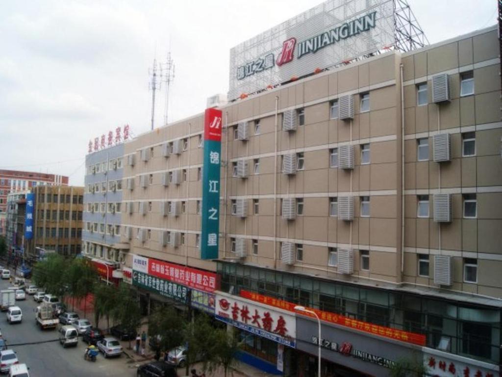 un edificio en una calle de la ciudad con coches en la carretera en Jinjiang Inn Changchun Railway Station New Branch, en Changchún