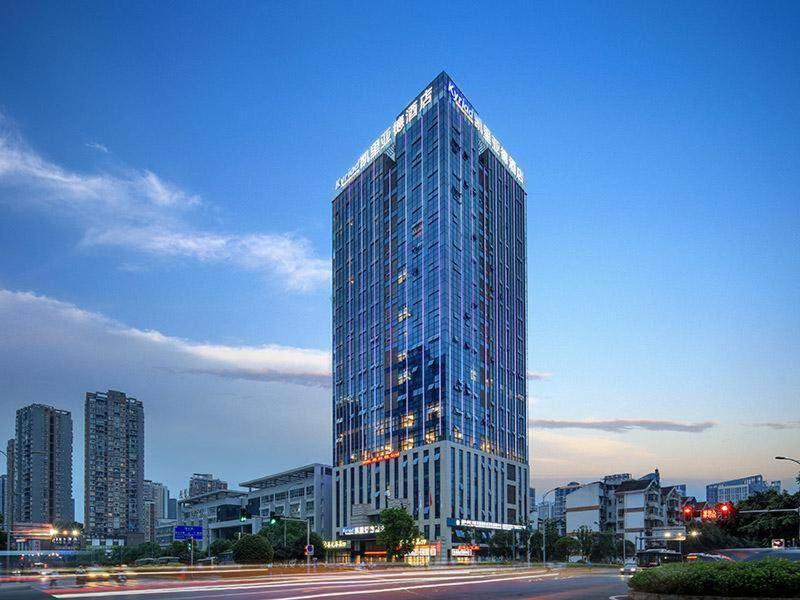 Kyriad Marvelous Hotel Chongqing North Railway Station في تشونغتشينغ: مبنى زجاجي طويل في مدينة عند الغسق