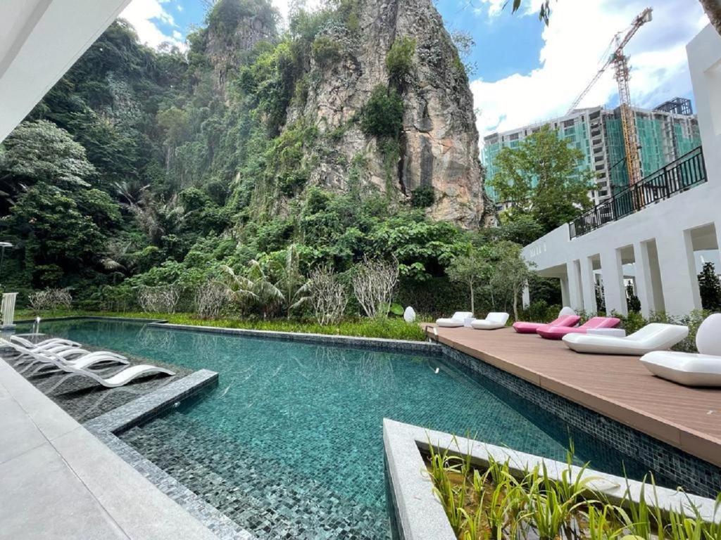 イポーにあるThe COVE at Ipoh Garden East 7 PAX Cozy Fully Air-Conのラウンジチェアと山のあるスイミングプールを併設しています。