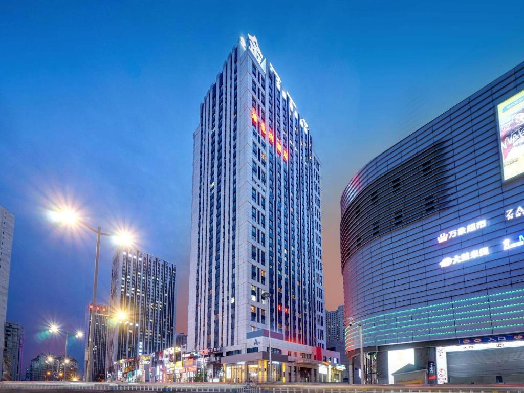 a tall building in a city at night at Vienna Hotel Harbin West Railway Station Wanda Plaza in Harbin