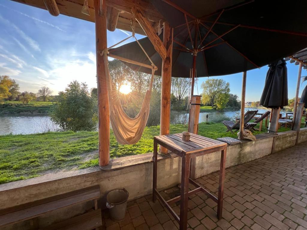 a table and an umbrella on a porch with a lake at Danubio an der Donau - Donau-Resorium in Donauwörth