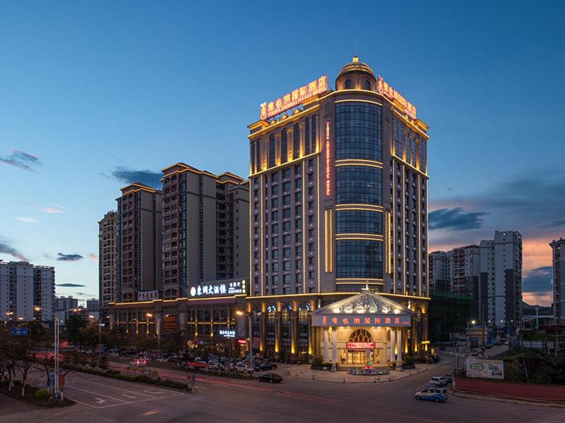 un grande edificio con luci sopra in una città di Vienna International Hotel ASEAN Avenue Dongxing a Fangcheng