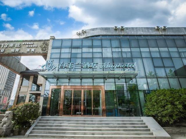 a large glass building with stairs in front of it at Magnotel Hotel Yangzhou Jinghua Wangyue Road in Yangzhou