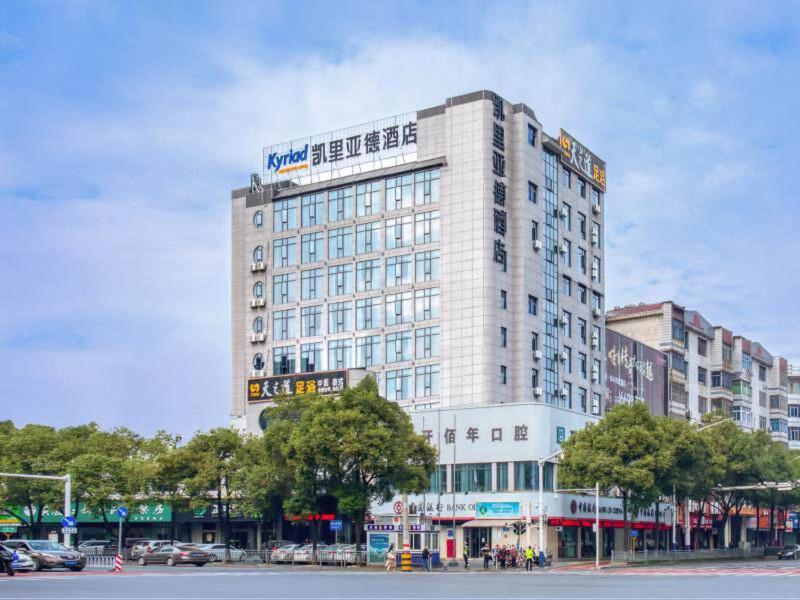 ein hohes weißes Gebäude mit einem Schild darüber in der Unterkunft Kyriad Hotel Pingxiang Wanlong Bay Branch in Pingxiang