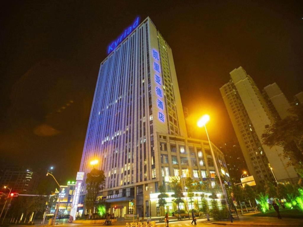 wysoki budynek z niebieskimi światłami w nocy w obiekcie Kyriad Marvelous Hotel Kunming High-Tech Zone Wuyue Plaza w mieście Kunming