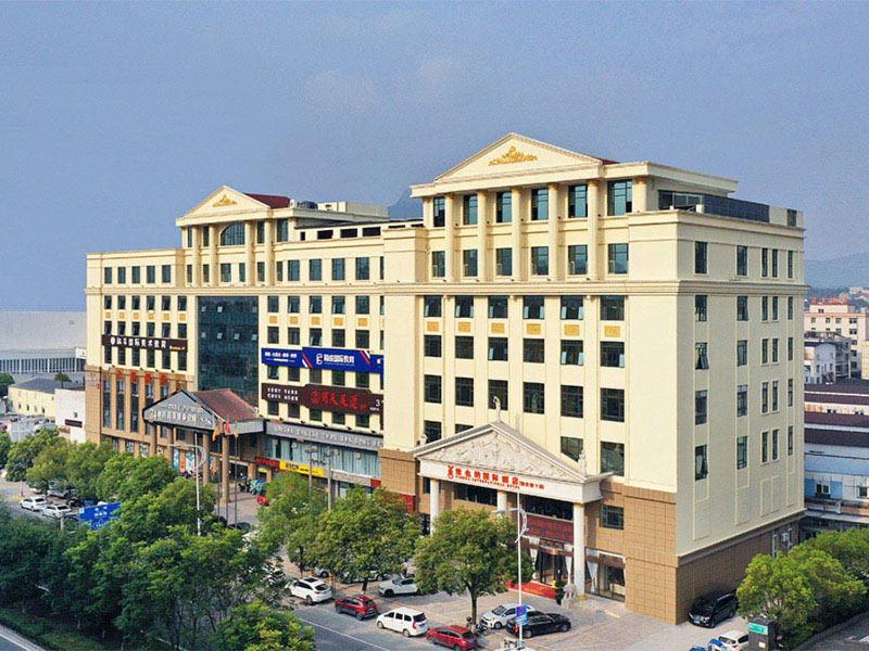 ein großes weißes Gebäude mit Autos auf einem Parkplatz in der Unterkunft Vienna International Hotel Zhejiang Wenzhou Ruian Tangxia in Ruian