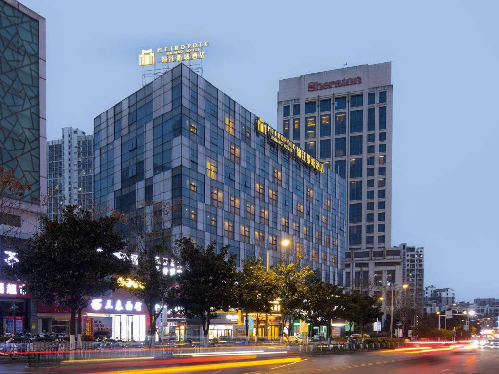 a large glass building in a city at night at Metropolo Hotel Zhenjia Wanda Plaza Railway Station in Zhenjiang