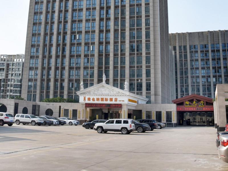 un aparcamiento con coches estacionados frente a un gran edificio en Vienna International Hotel Yangzhou Wanda Lippo Plaza, en Yangzhou