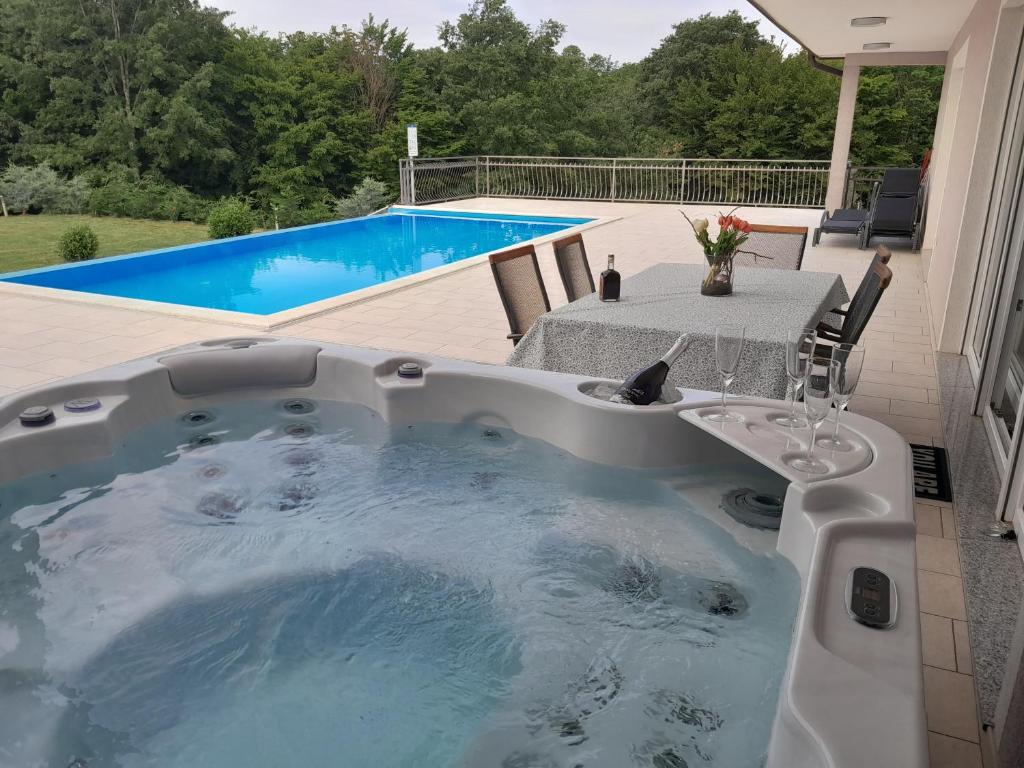 un bain à remous sur une terrasse avec une table et une piscine dans l'établissement Villa Heaven Green, à Pazin