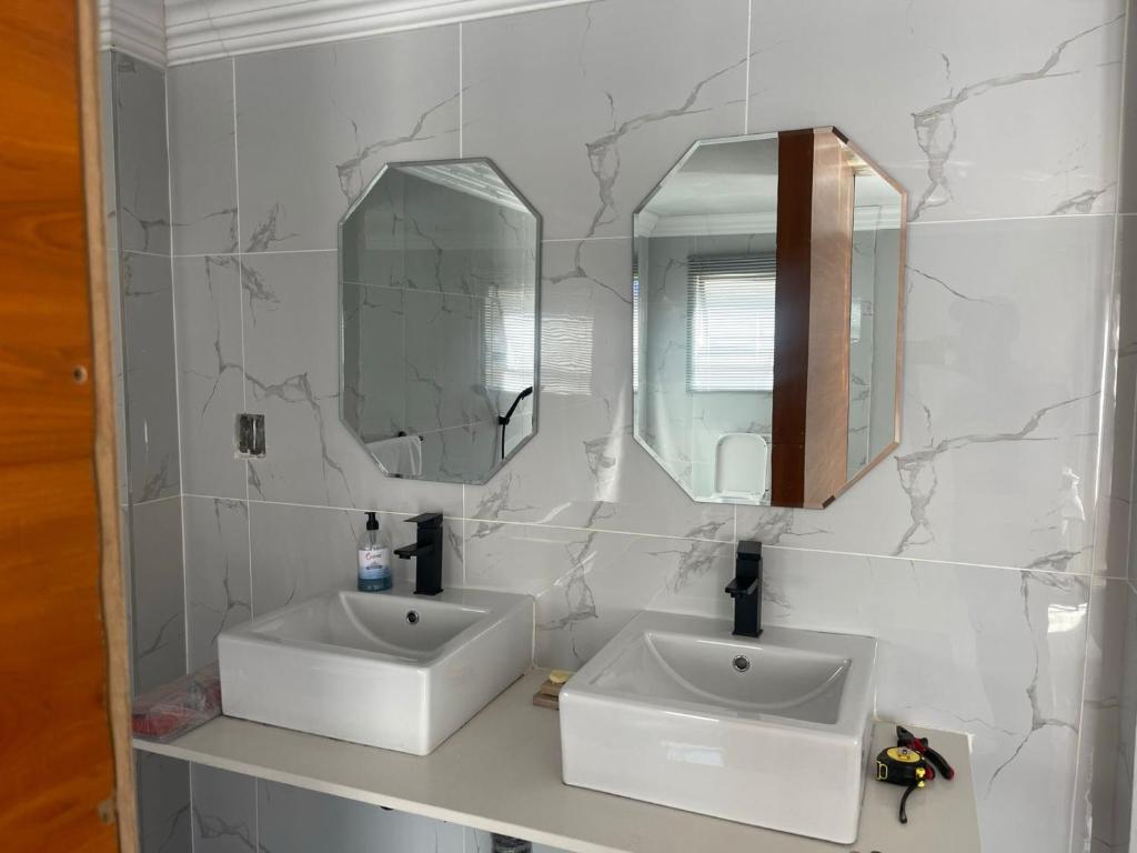 a bathroom with two sinks and two mirrors at Mo'Acress Lifestyle in Temba
