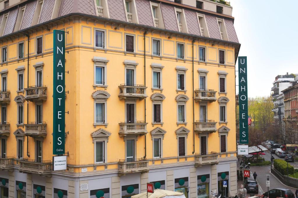 un edificio giallo con cartelli sul lato di UNAHOTELS Galles Milano a Milano