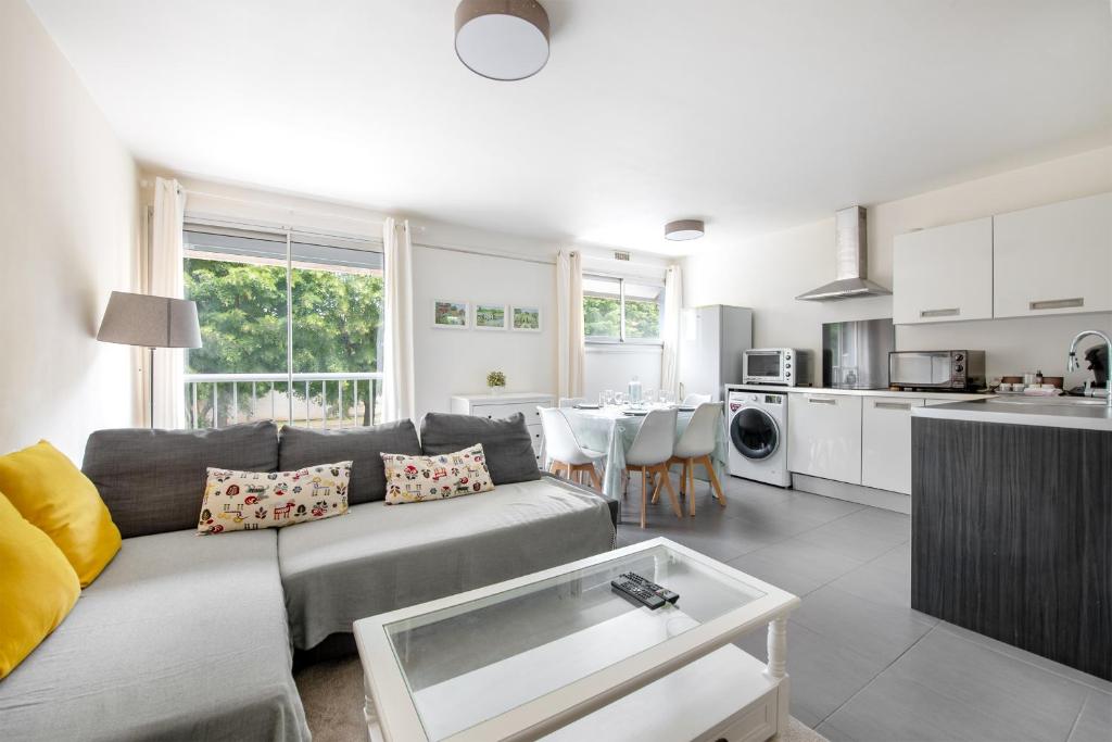 Il comprend un salon avec un canapé gris et une cuisine. dans l'établissement Le Corbusier - T3 atypique et spacieux, à Toulouse