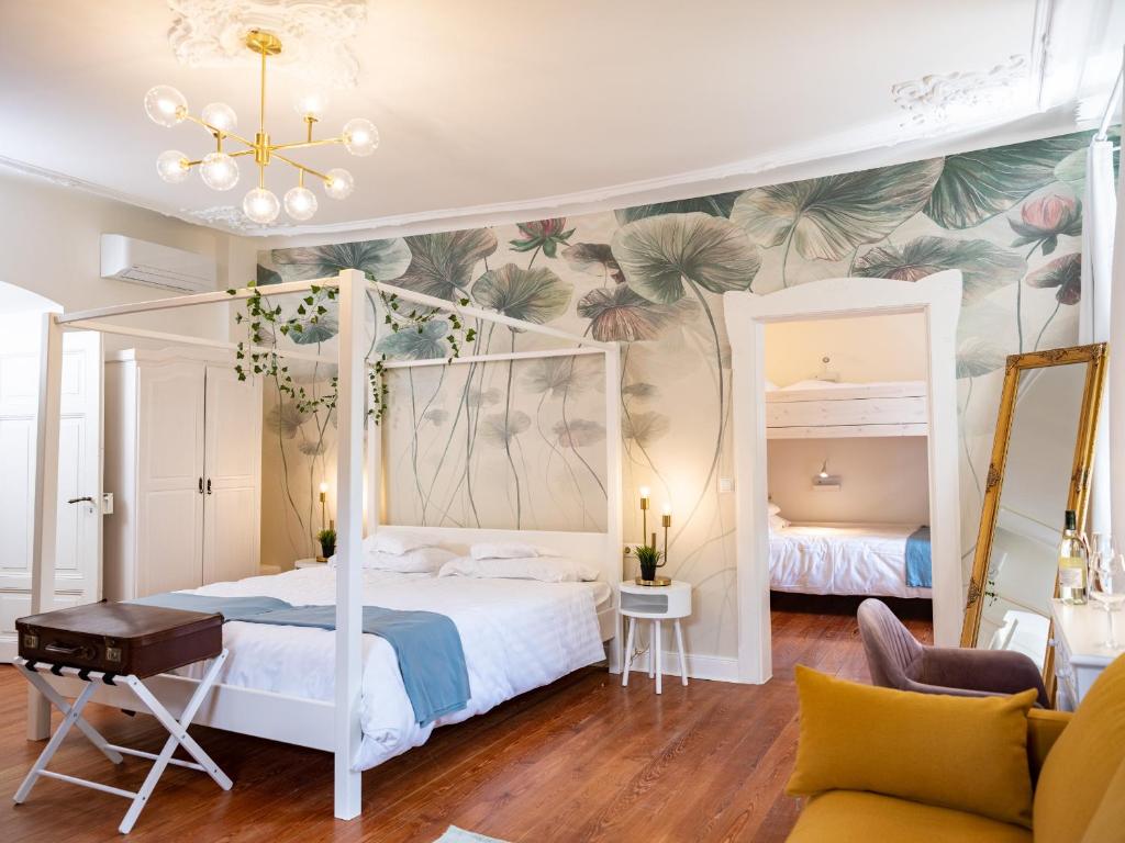 a bedroom with a white canopy bed with a tropical wallpaper at Gästehaus Schloss Janson 