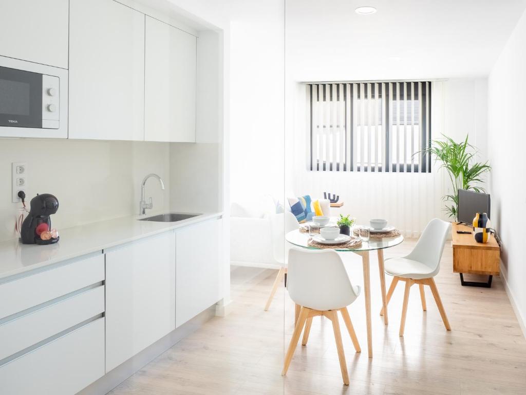 uma cozinha com armários brancos e uma mesa e cadeiras em Apartment Abora with Pool, Gym and Free Parking em Las Palmas de Gran Canárias