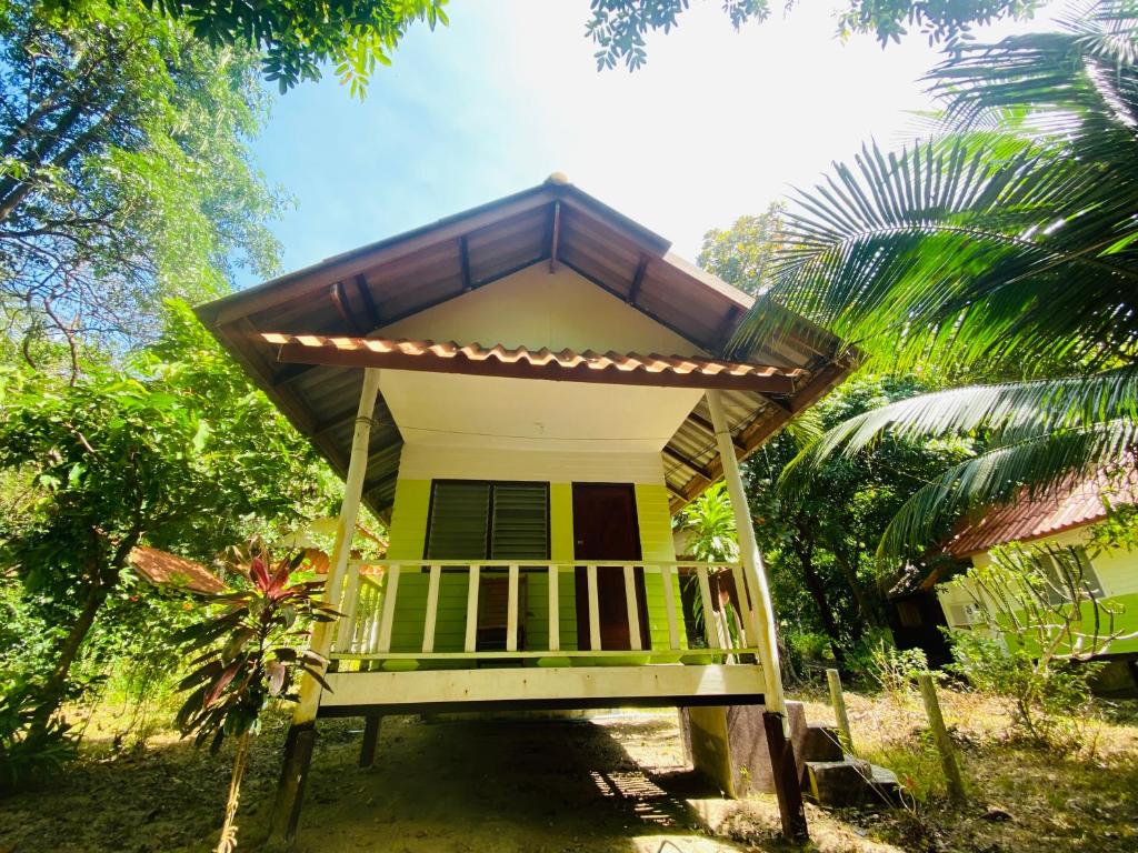 a small house with a balcony in a forest at Banana Resort in Ko Phayam