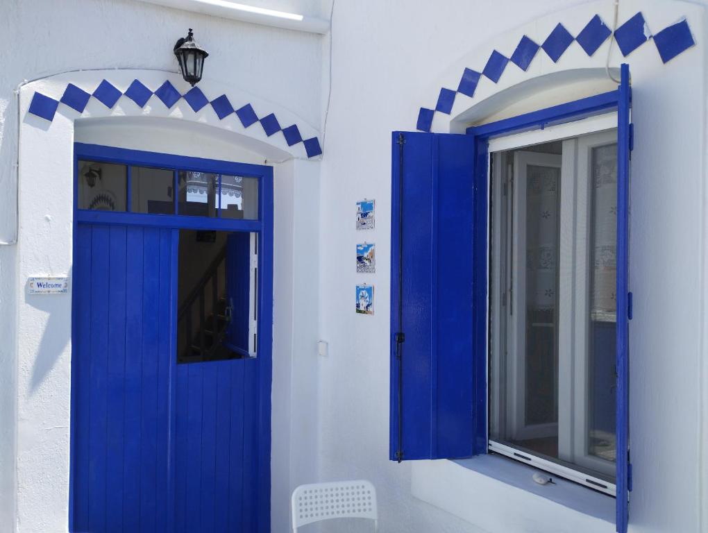 een blauwe deur en een spiegel op een witte muur bij Mari...Milo in Péran Triovasálos