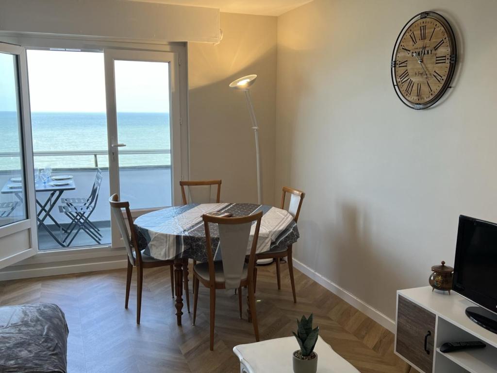 une salle à manger avec une table et une horloge au mur dans l'établissement Studio cabine avec parking près de la plage - FR-1-487-353, à Varaville