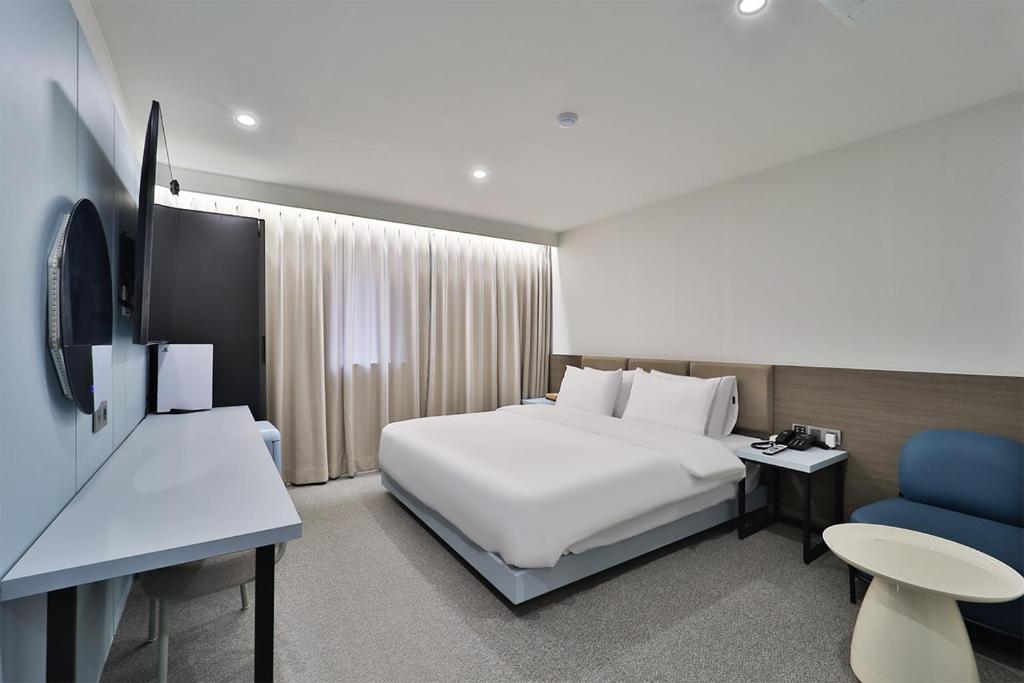 Habitación de hotel con cama blanca y silla azul en DOAN STAY HOTEL, en Ulsan