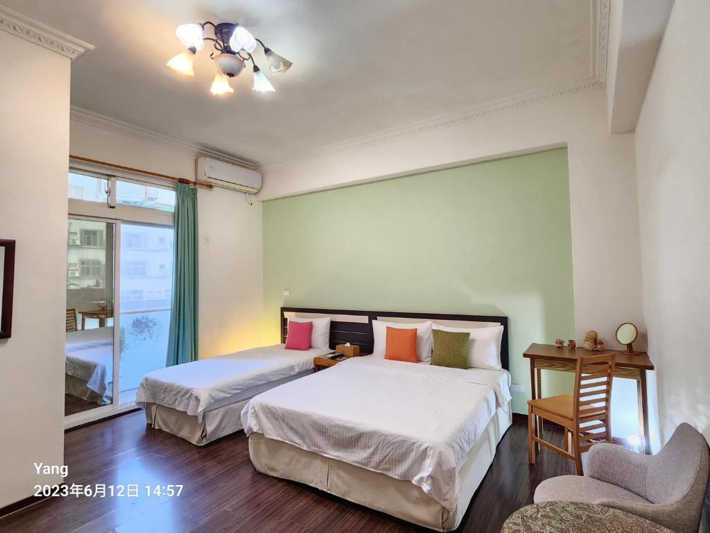a bedroom with two beds and a chair and a window at East of Love Homestay in Hualien City