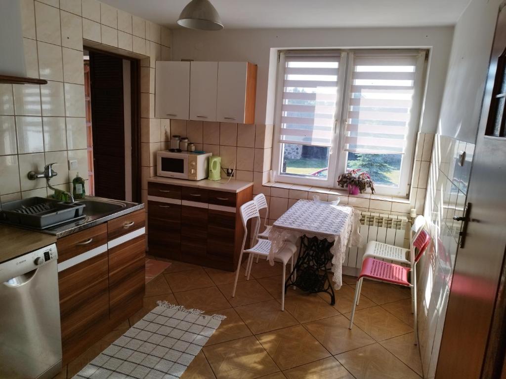 a kitchen with a table and chairs and a microwave at Zakątek Pod Lasem in Wydminy