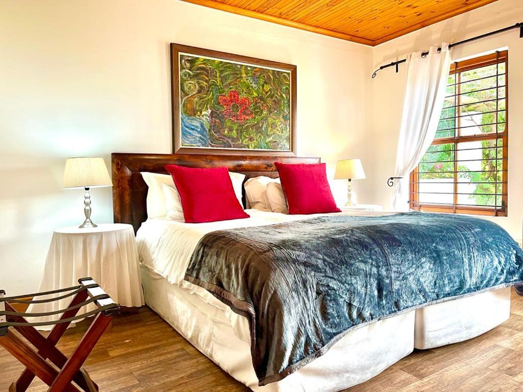 a bedroom with a large bed with red pillows at Eikelaan Farm Cottages in Tulbagh