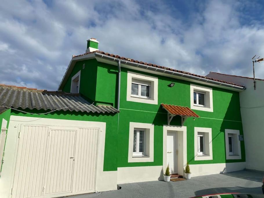 una casa verde y blanca con garaje en La Casa Verde, 