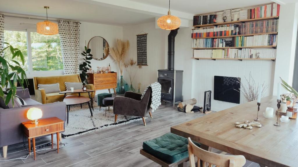 a living room with a table and a fireplace at Oasis de tranquiillité in Quend