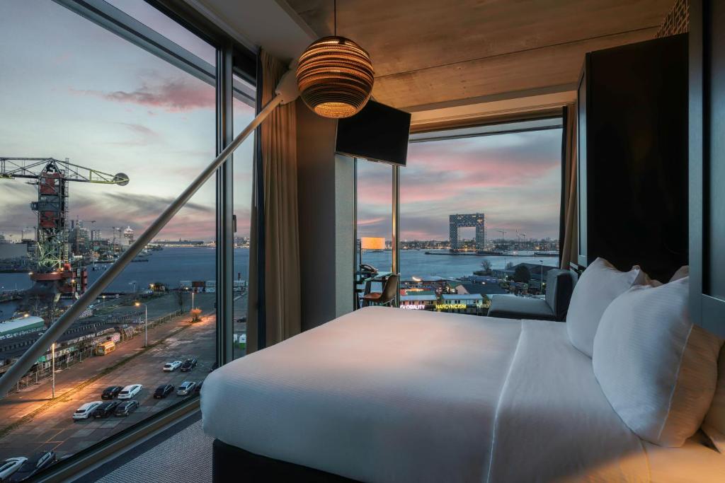 a bedroom with a bed and a view of a city at DoubleTree by Hilton Amsterdam - NDSM Wharf in Amsterdam