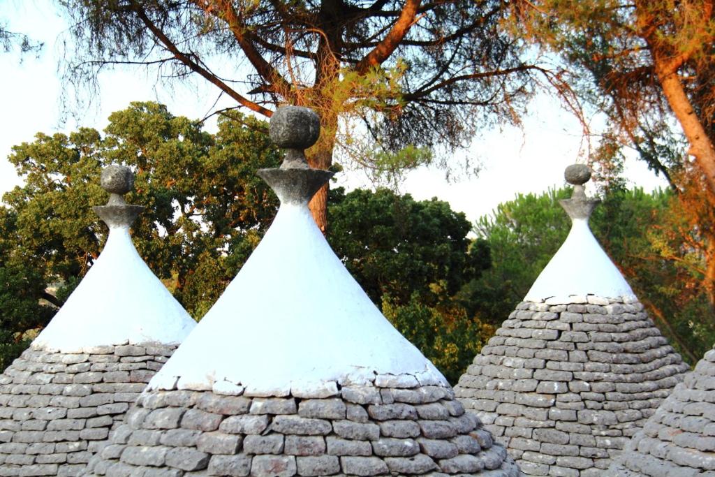 uma linha de telhados pontiagudos com árvores ao fundo em Villa Tessi em Cisternino
