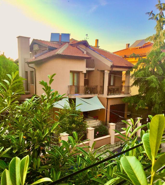 a large house with a balcony and trees at Dimitrovi Guesthouse - Peaceful Stay near Beach with Garden, Sarafovo in Burgas