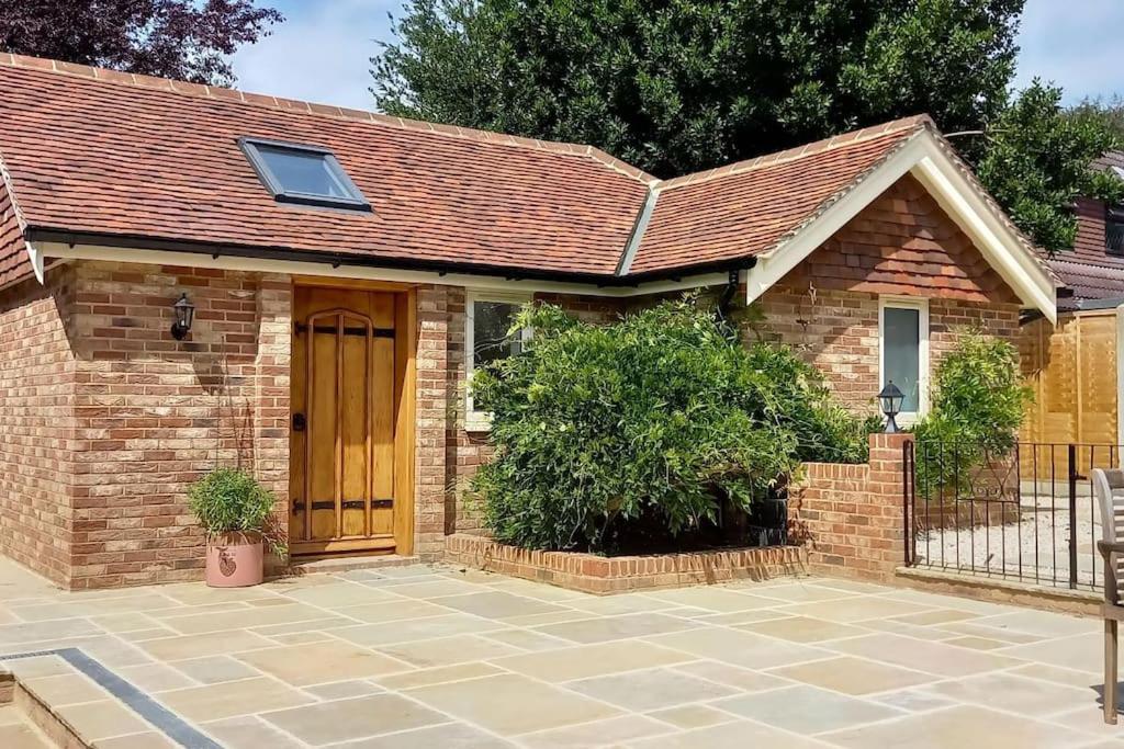 a brick house with a wooden door and a courtyard at Brand new annexe on border of the Southdowns. in Waterlooville