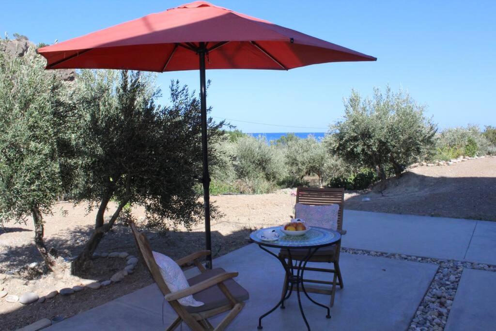 a patio with a table and a red umbrella at Ferienwohnung direkt am Strand in Ierapetra