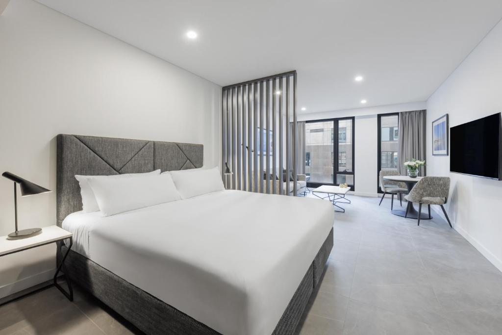 a bedroom with a large white bed and a desk at Meriton Suites King Street Melbourne in Melbourne