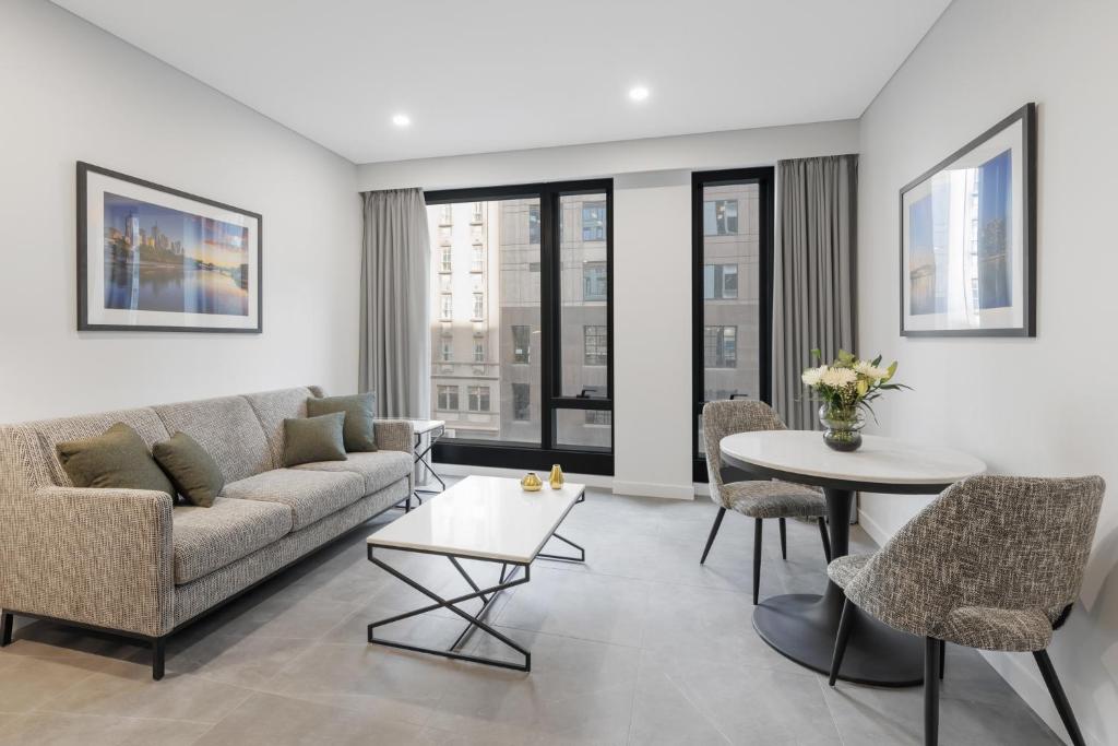 a living room with a couch and a table and chairs at Meriton Suites King Street Melbourne in Melbourne