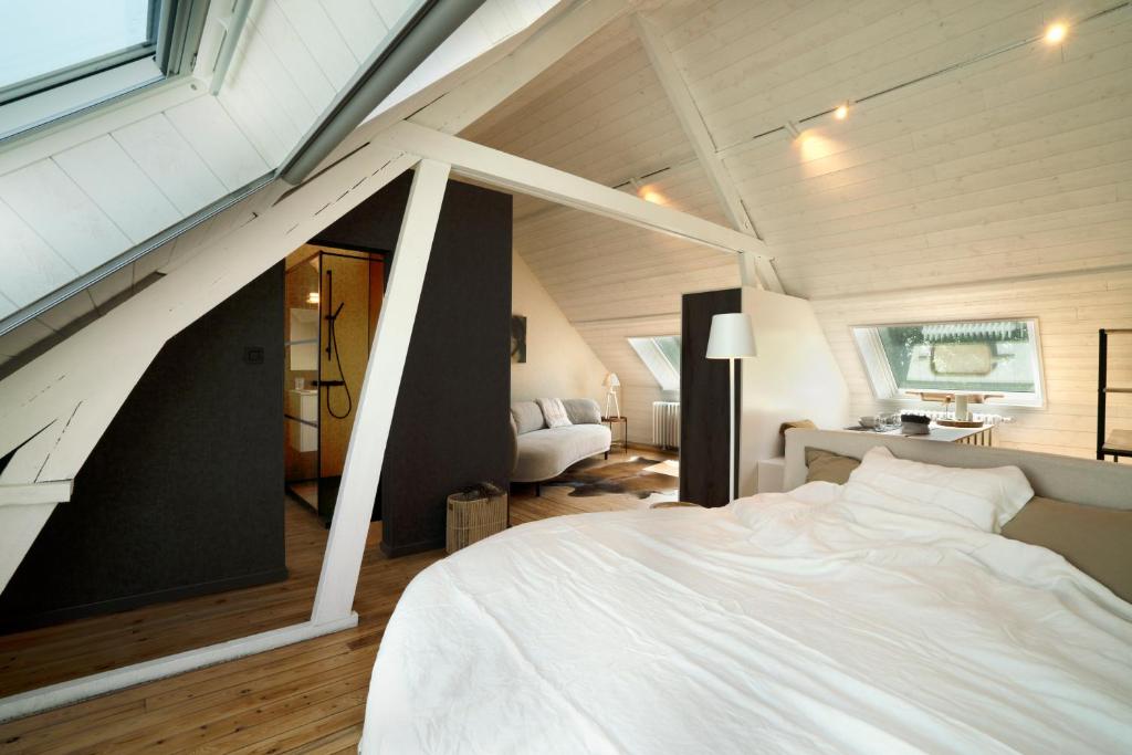 um quarto com uma cama branca num sótão em Battre d'eau, verborgen b&b aan het water em Diksmuide