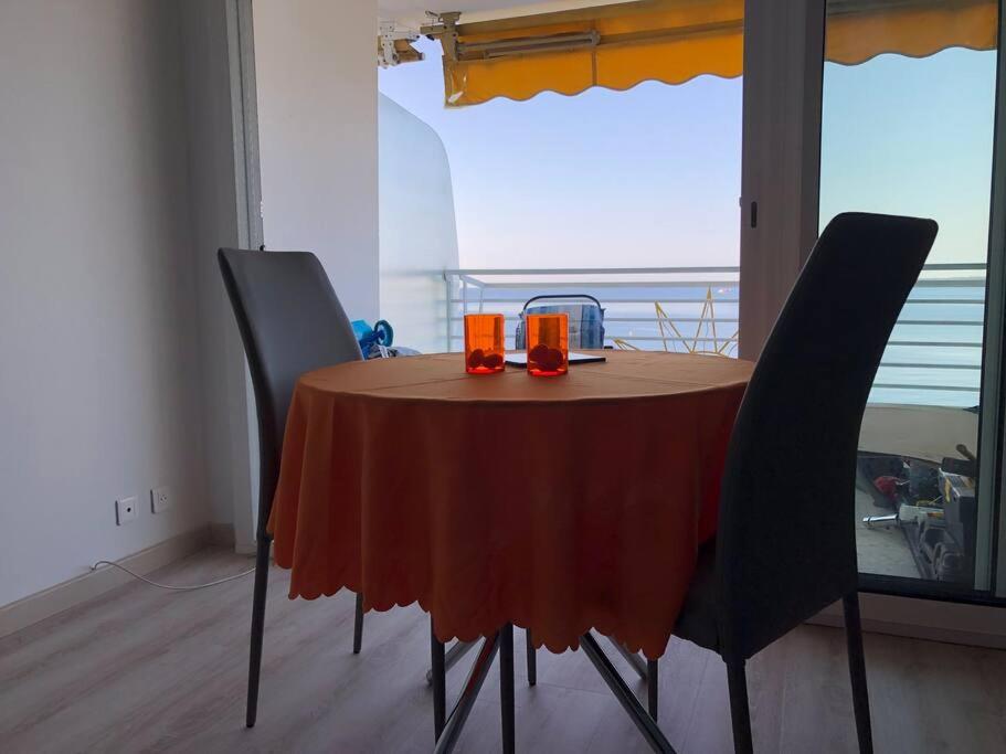 a dining room table with two orange glasses on it at Soleil 2023 in Antibes