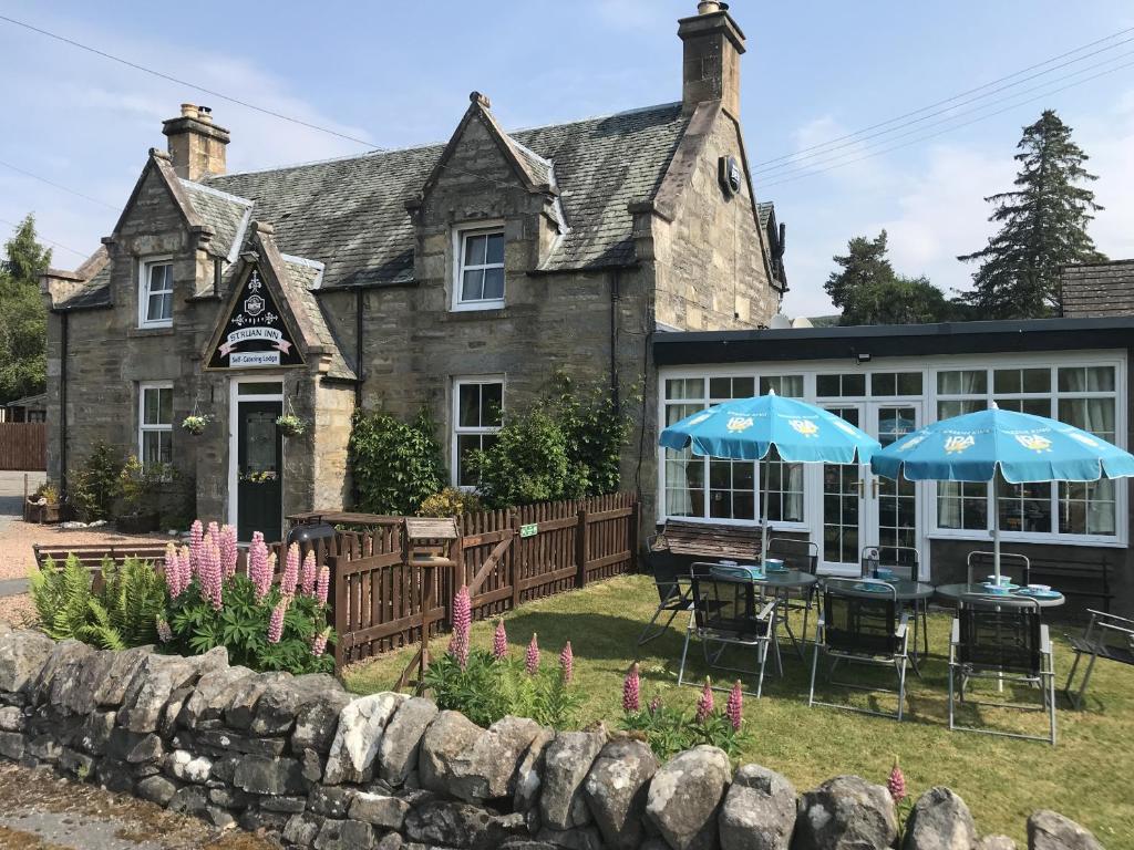 a house with two blue umbrellas in front of it at The Struan Inn Self Catering Lodge in Struan