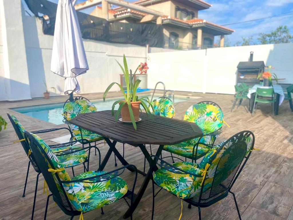 una mesa con sillas y una sombrilla junto a la piscina en Casa Campoamor By Solymar Holiday en Cogollos de Guadix