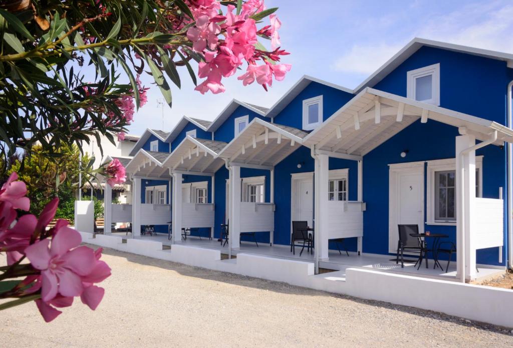 a row of blue and white beach huts with pink flowers at Nafsika Suites in Nea Moudania