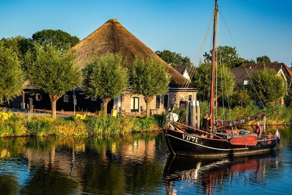 een boot in het water voor een huis bij Loft in romantische stolpboerderij bij duingebied. in Warmenhuizen