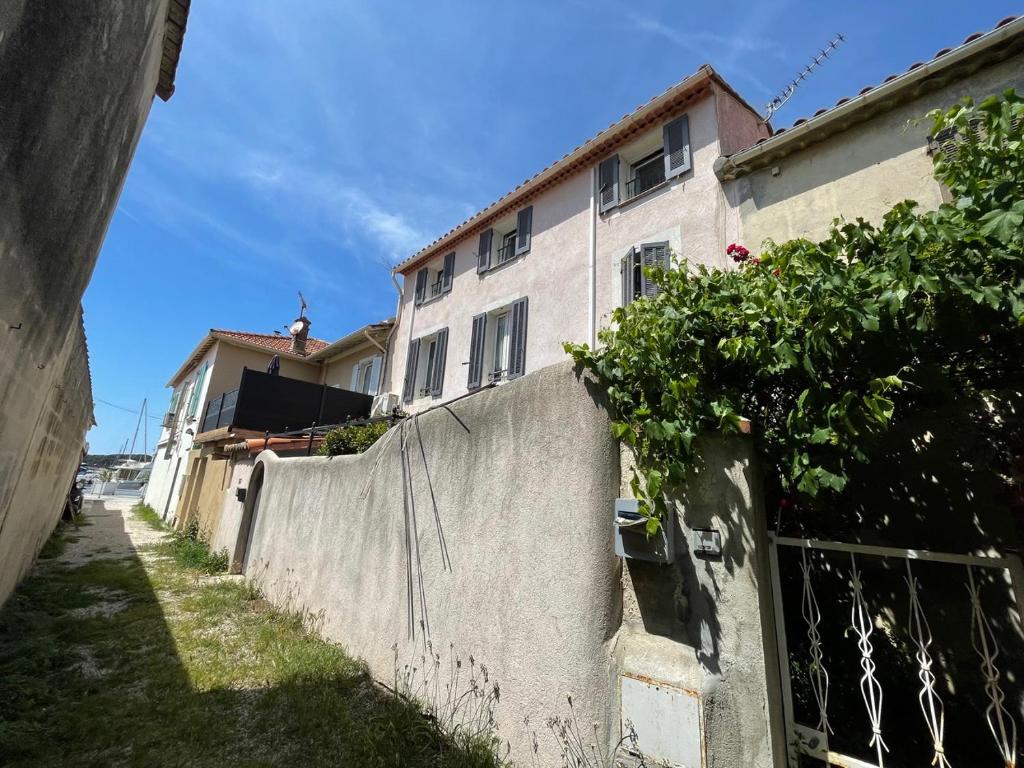 une clôture devant un bâtiment à côté d'une maison dans l'établissement Coquillage bleu, à Six-Fours-les-Plages