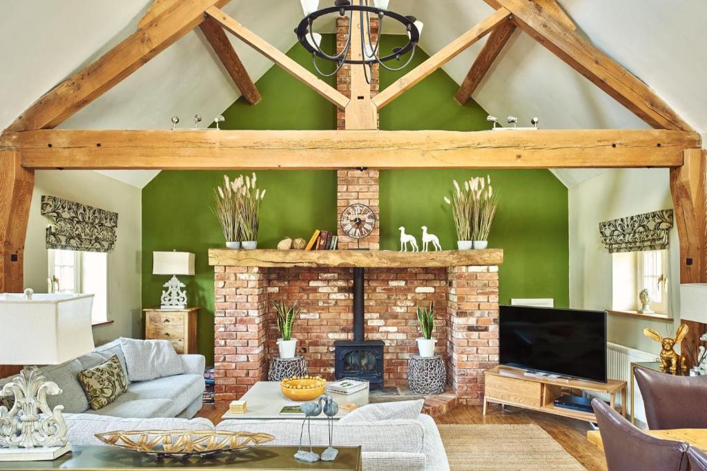 a living room with a brick fireplace and green walls at Hollington Barns in Ashbourne